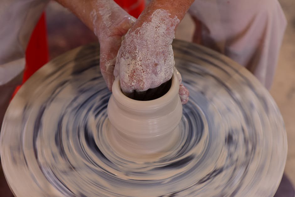 Hands shaping clay on a pottery wheel in a sunlit studio