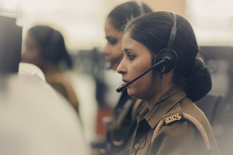 911 dispatcher at console with hand on headset processing emotional call