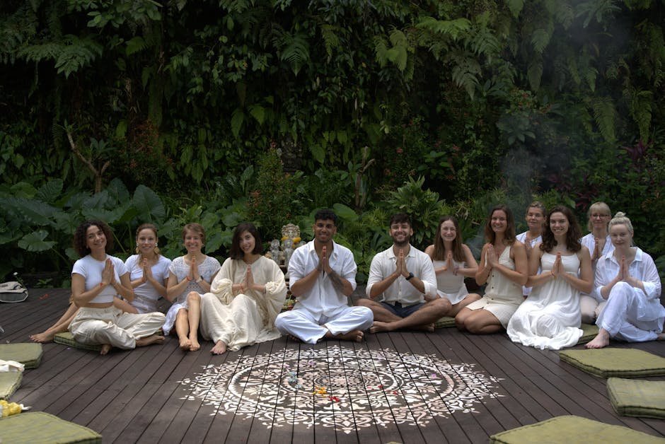 Yoga retreat group meditating outdoors at sunrise on coastal platform with ocean view