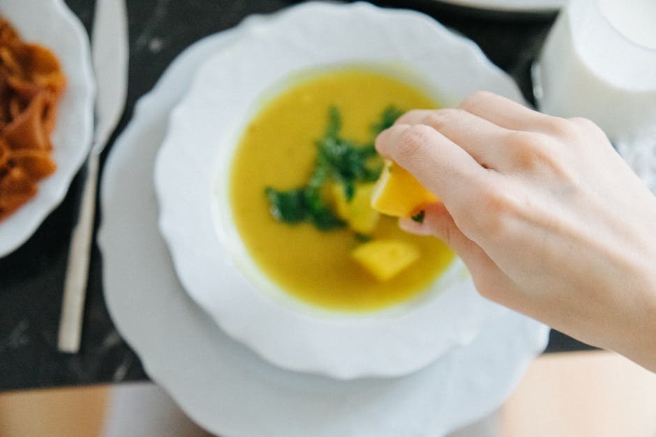 Bowl of lentil and vegetable soup with whole grain bread on a wooden table