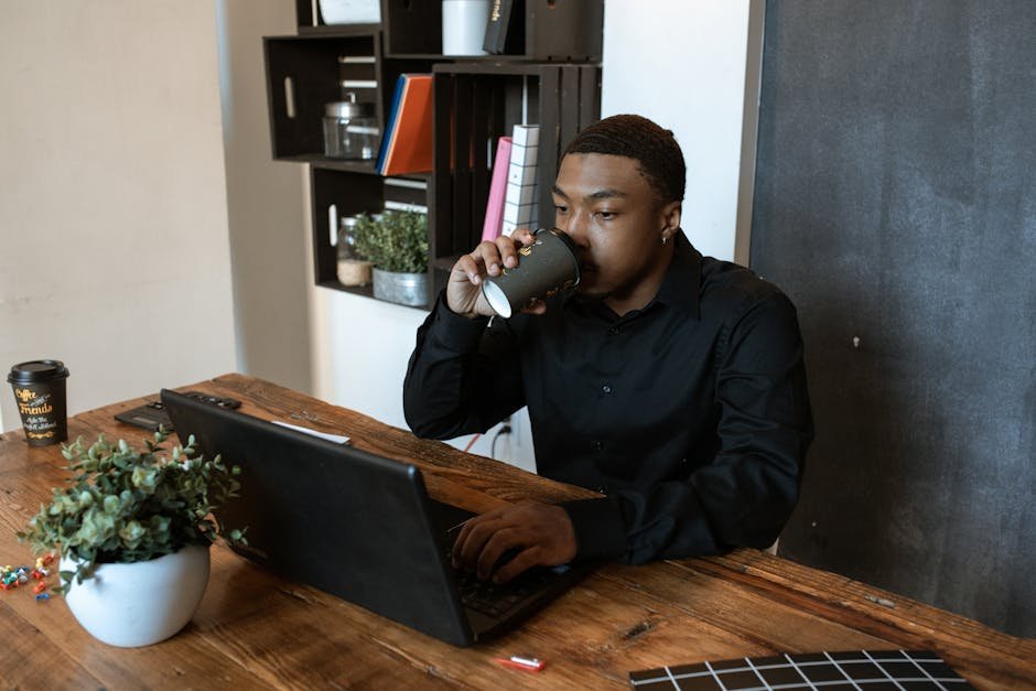 Black man on laptop in home office during telehealth therapy session
